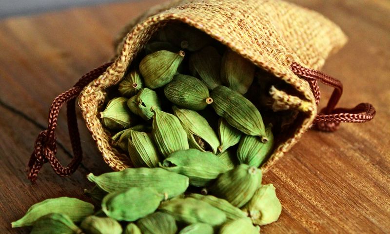 Vagens de cardamomo verde sobre mesa de madeira rústica