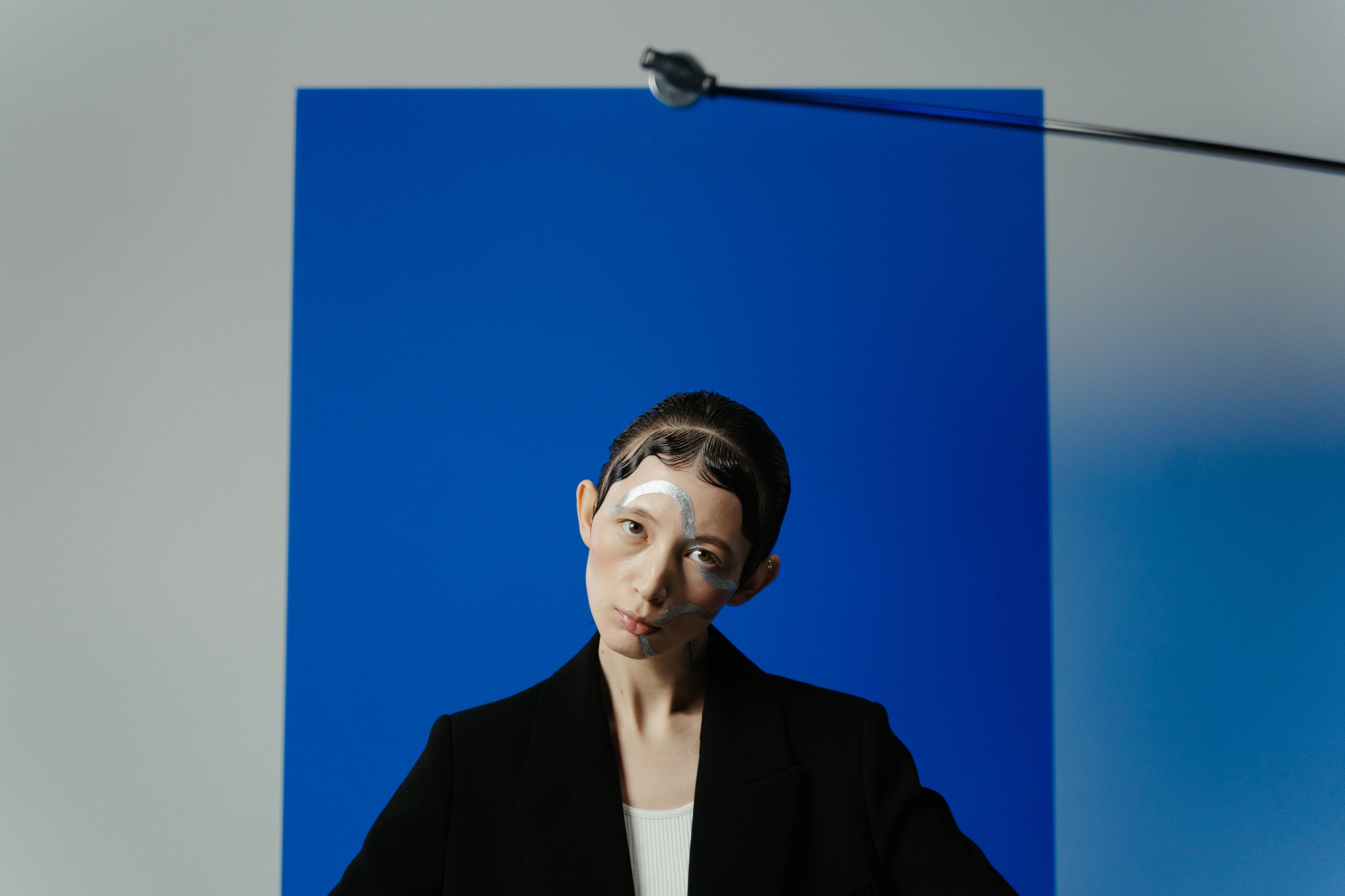 Conceptual photo of a woman with creative makeup posing against a blue background in a studio.