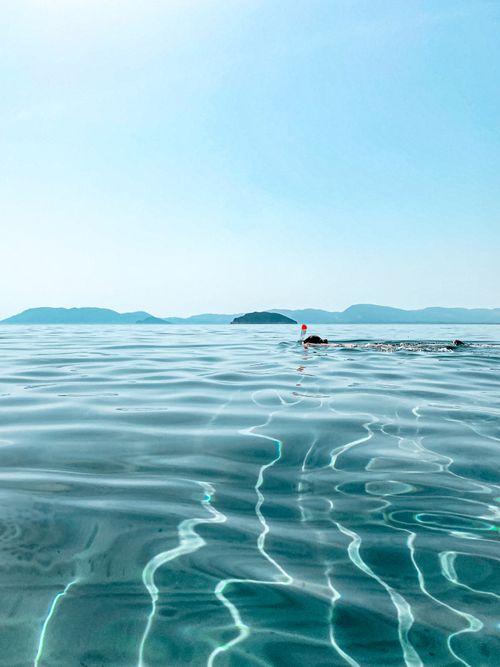 Free Serene swimming experience in the clear waters of the Ionian Sea, Zakinthos under a bright blue sky. Stock Photo