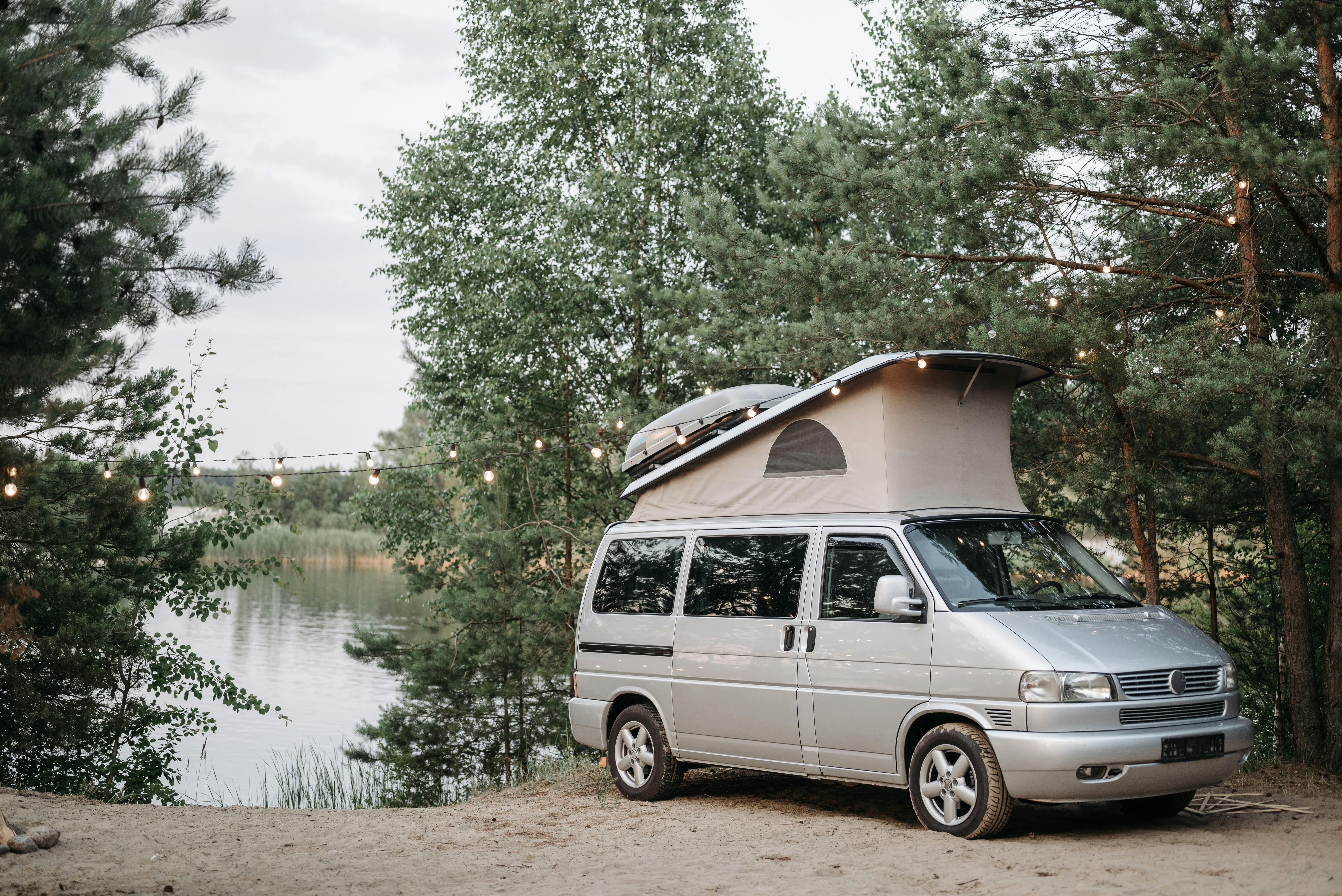 A campervan parked at a lakeside campsite surrounded by trees, ideal for outdoor adventures.