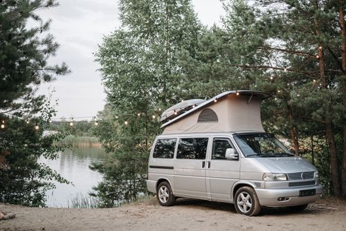 Free A campervan parked at a lakeside campsite surrounded by trees, ideal for outdoor adventures. Stock Photo