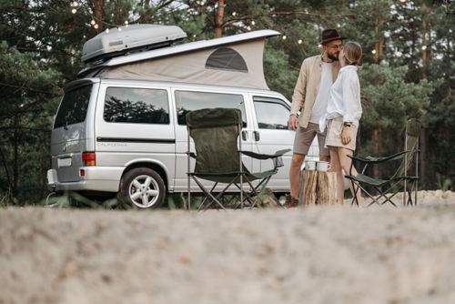 Free A couple shares a romantic moment by their camper van in a serene outdoor setting. Stock Photo