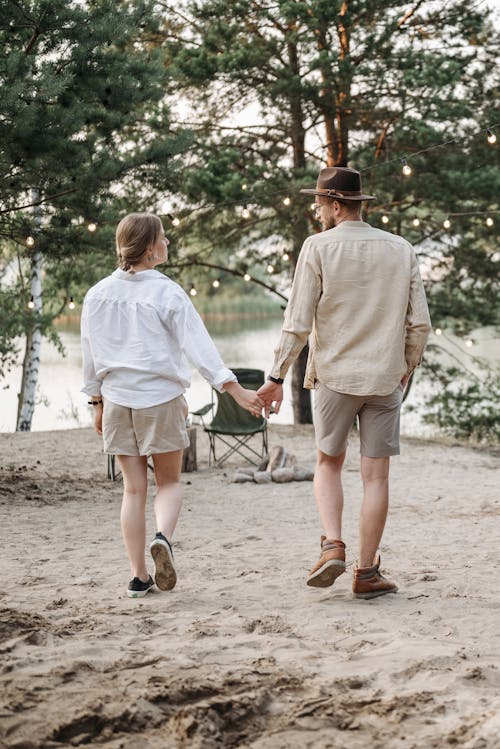 Couple Holding Hands While Walking on Sand