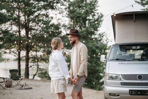 Free Couple holding hands by their campervan at a scenic outdoor campsite. Stock Photo