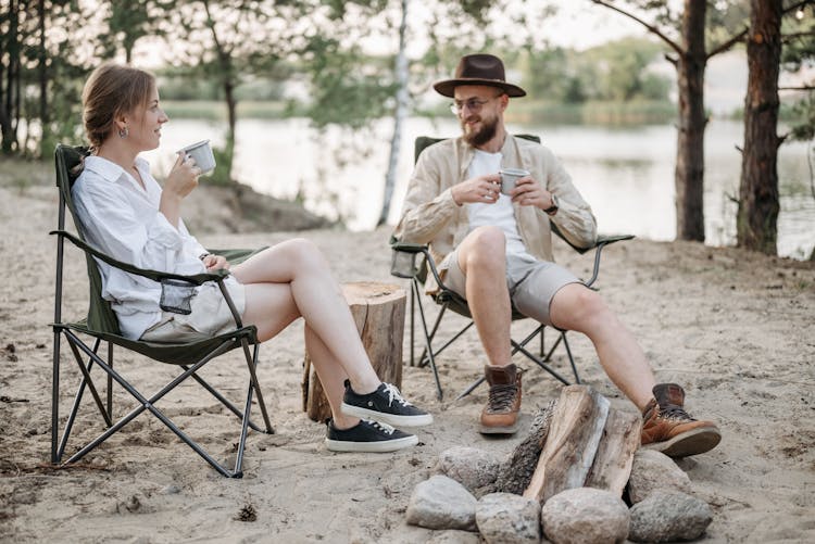 Man And Woman Sitting On Camping Chairs