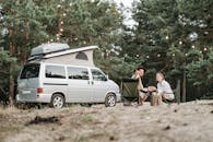 Man and Woman Sitting on Chairs Near White Van
