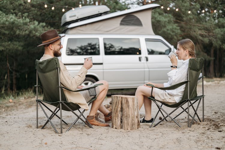 Couple Sitting On Camping Chair Drinking Coffee