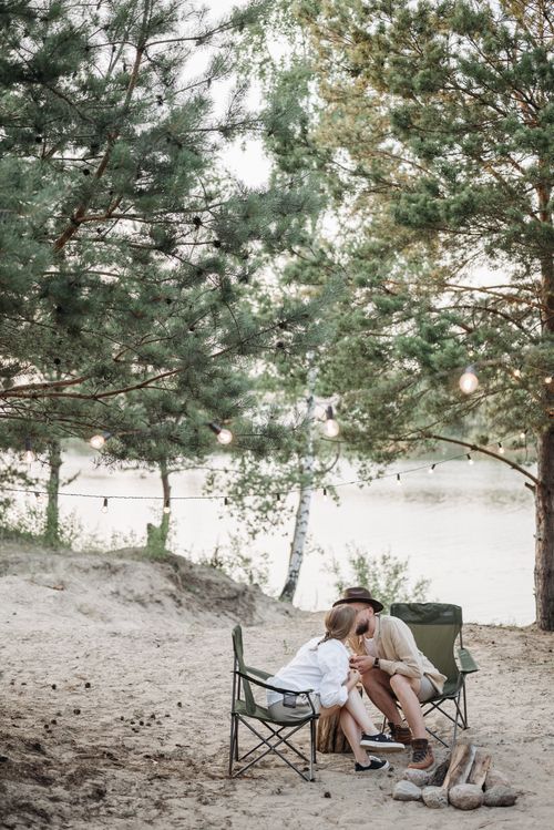 Free Couple enjoying a romantic moment while camping by the river under trees. Stock Photo