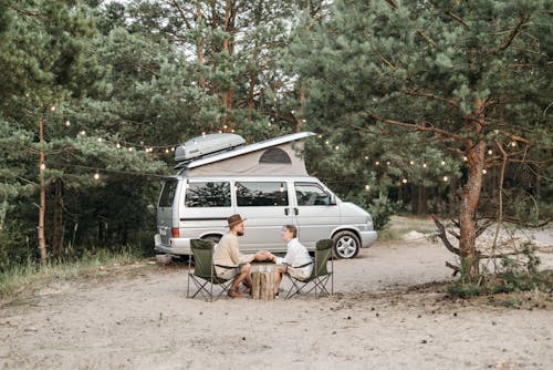 Couple Sitting on Chairs Beside a Van