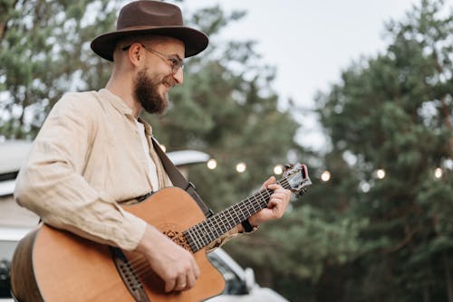 A Bearded Man Smiling while Playing Guitar