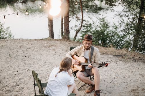 Free A romantic guitar serenade by the lake, perfect outdoor evening experience. Stock Photo