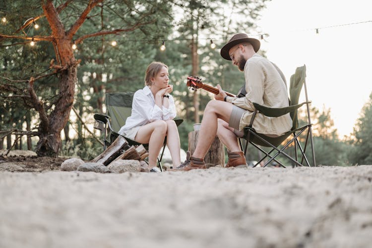 A Woman In White Long Sleeves Looking At The Man Playing Guitar