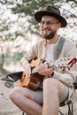 Man in White Dress Shirt and Brown Fedora Hat Playing Brown Acoustic Guitar