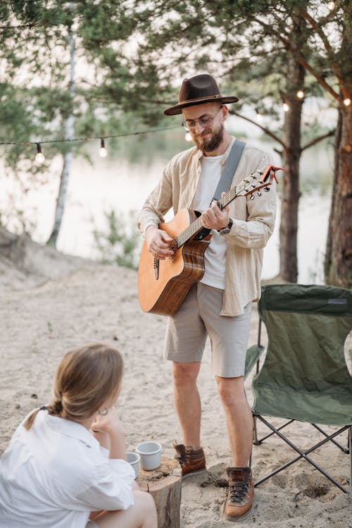 A Bearded Man Playing an Acoustic Guitar while Standing