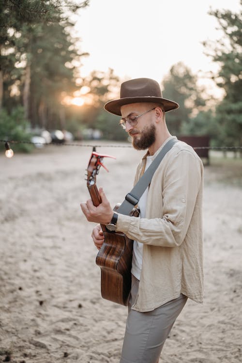 A Bearded Man Wearing Brown Hat while Playing Guitar