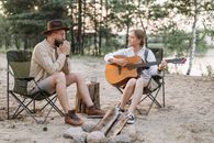 A Couple Sitting on Folding Chairs while Playing Musical Instruments