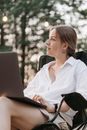 A Woman in White Long Sleeves Sitting on the Chair while Using Her Laptop