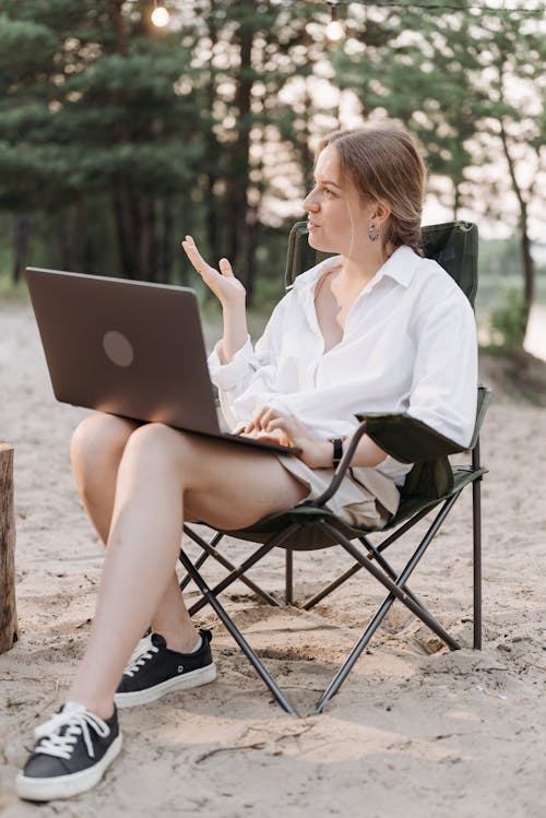 Pretty Woman Sitting on a Folding Chair Using a Laptop