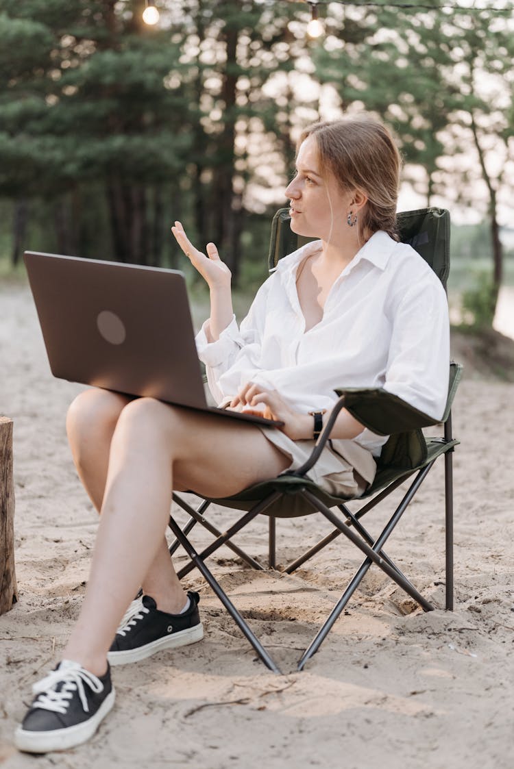 Pretty Woman Sitting On A Folding Chair Using A Laptop