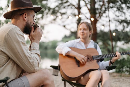 A Man Playing Harmonica while Looking at the Woman Playing Guitar