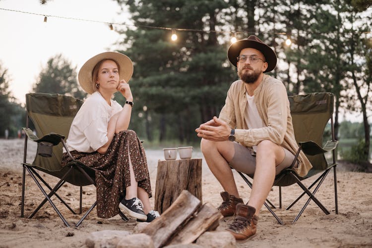 A Man And Woman Sitting On The Camping Chairs