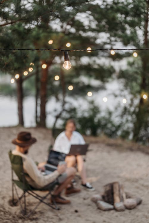 A String of Lights Bulbs Over a Couple Sitting Outdoors