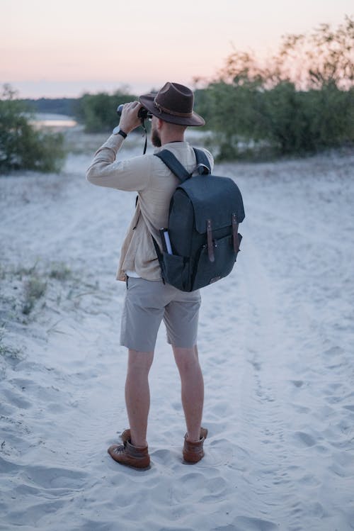 Free Man in Long Sleeve Shirt and Shorts with Black Backpack Holding Binoculars Stock Photo