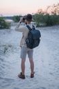 Man in Long Sleeve Shirt and Shorts with Black Backpack Holding Binoculars