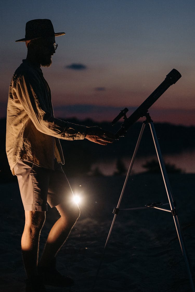 A Man With Hat Holding A Telescope