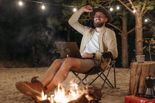 Man Sitting with a Laptop by a Bonfire on a Beach 