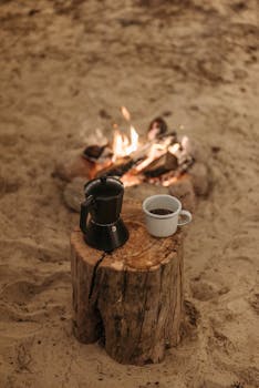 A serene campfire setting with coffee and moka pot on a wooden log, perfect for outdoor lovers.