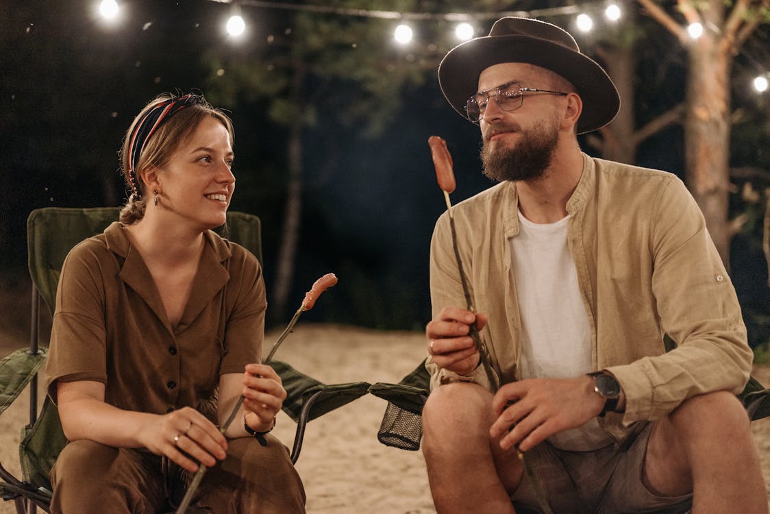 A Couple Holding a Wooden Sticks with Food while Having Conversation
