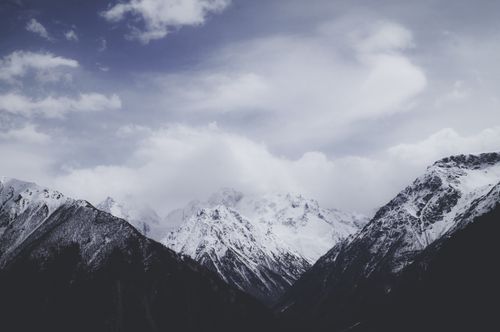 Free Majestic snowy mountains under a cloudy sky, offering a breathtaking and serene winter landscape. Stock Photo