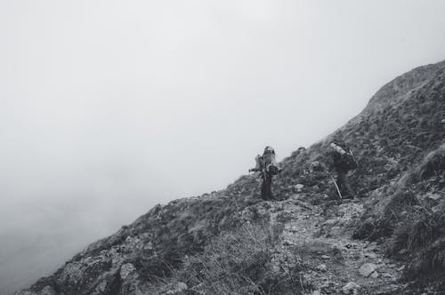 Free A Grayscale Photo of People Hiking on Mountain Stock Photo