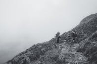 A Grayscale Photo of People Hiking on Mountain