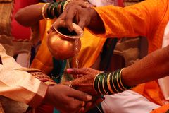 Colorful close-up of a traditional Indian wedding ceremony with water pouring ritual.