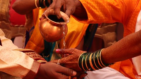 Colorful close-up of a traditional Indian wedding ceremony with water pouring ritual.