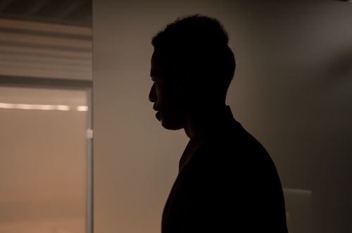 Free A dramatic silhouette of a man viewed from the side in an indoor setting, creating a moody atmosphere. Stock Photo