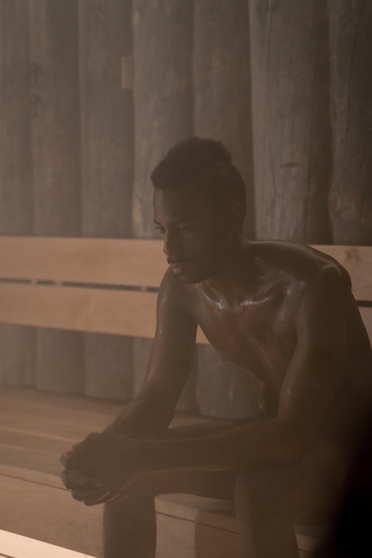 A Shirtless Man Sitting Inside The Sauna