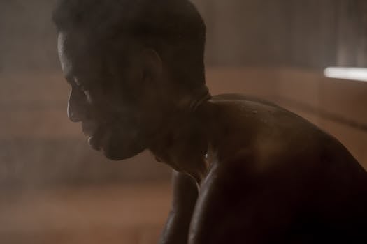 Side view of an adult man relaxing in a steamy sauna, focusing on wellness and self-care.
