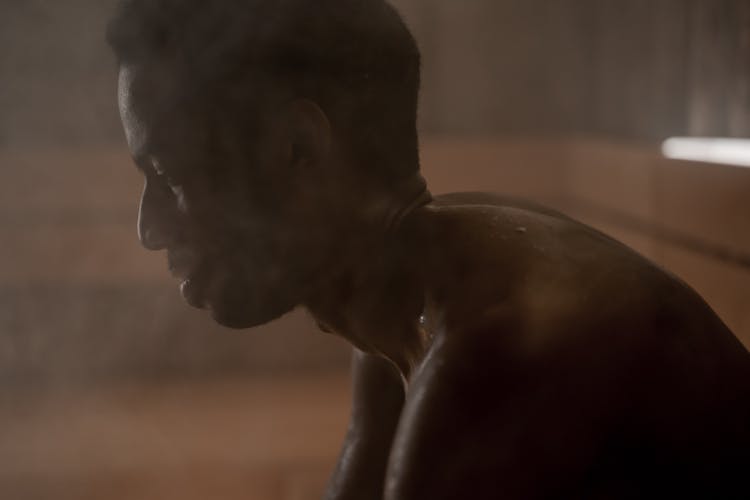 A Side View Of A Shirtless Man Sweating