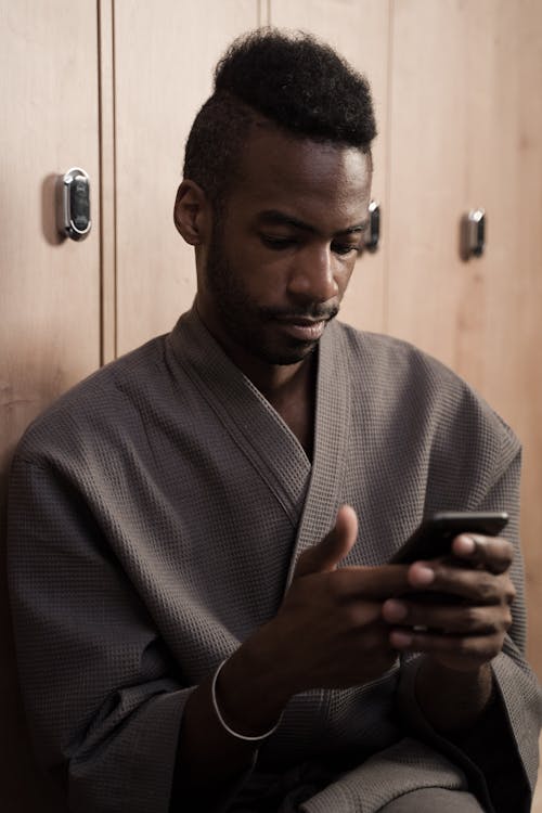 A Man in a Robe Using His Phone in the Dressing Room