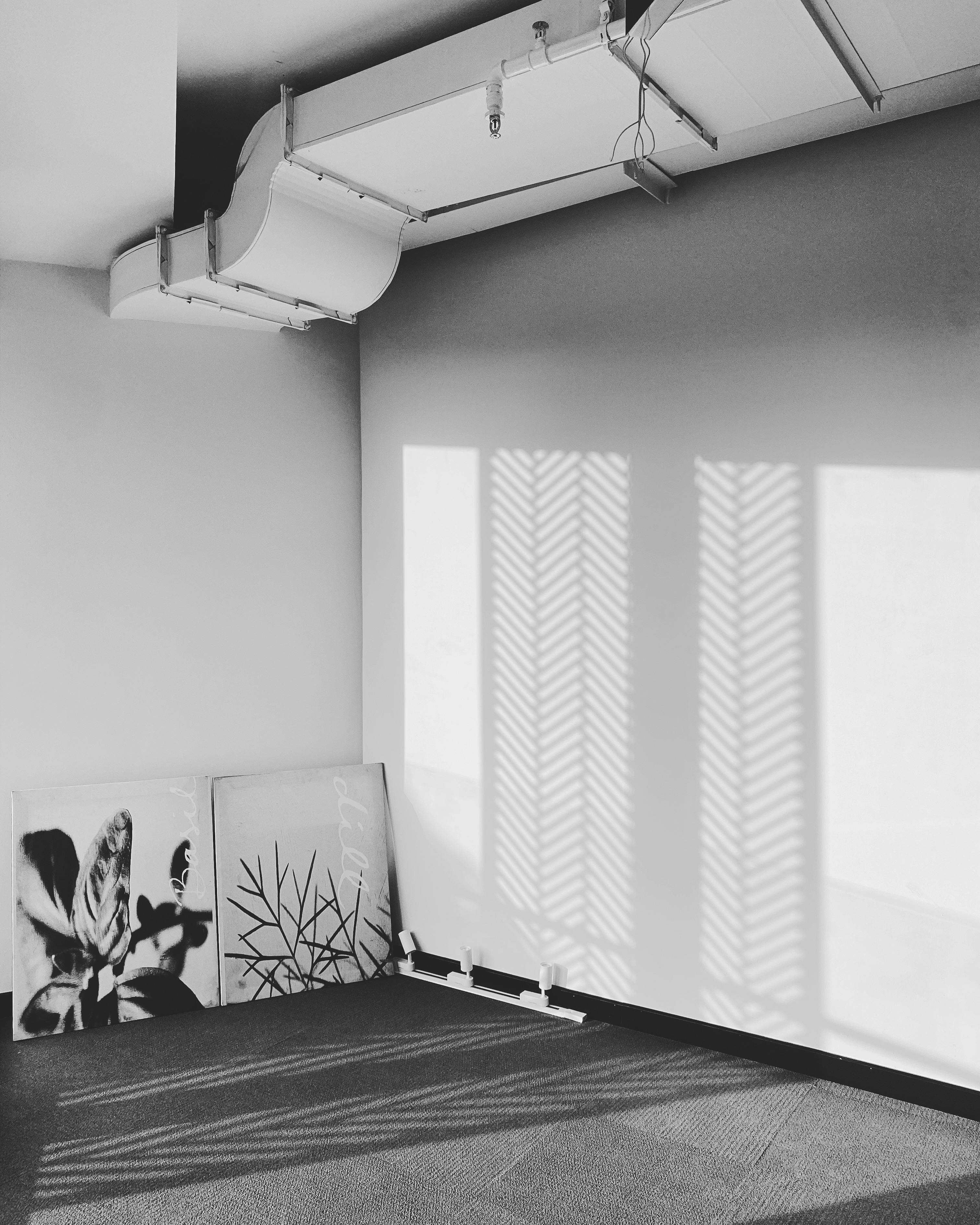 A minimalist room with shadow patterns and black and white art on the wall.