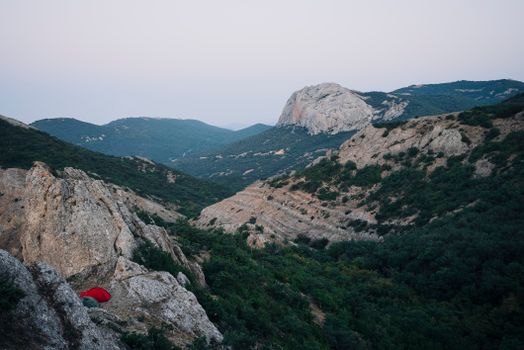Peaceful mountain landscape at twilight with a red tent in the valley.