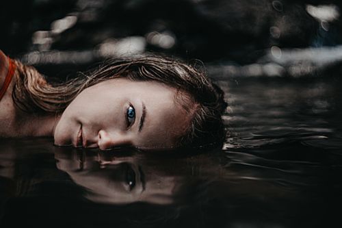 Free Close-up artistic portrait of a woman reflecting in water, evoking a serene and contemplative mood. Stock Photo