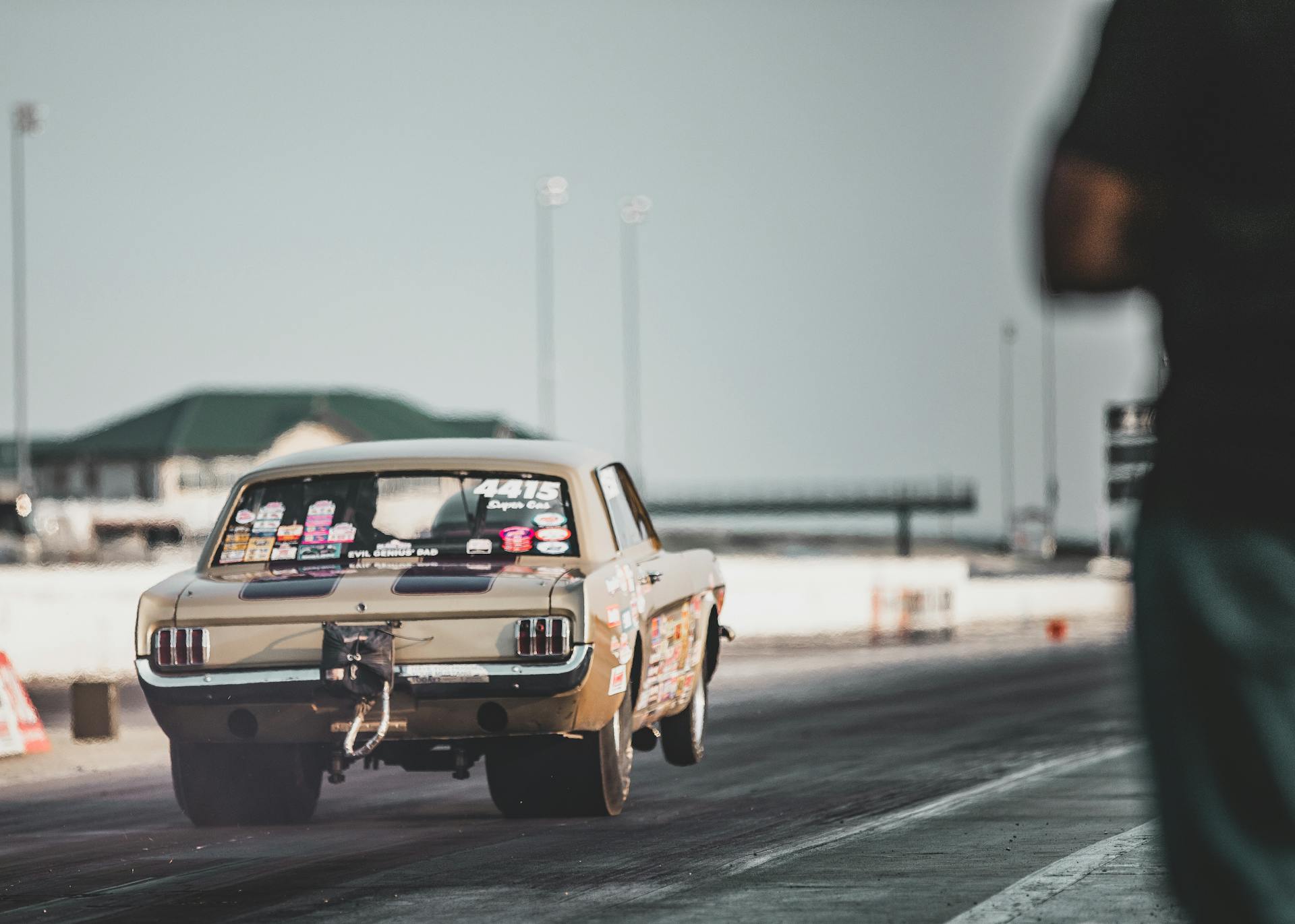 A racing car accelerates on a Topeka race track under clear skies.