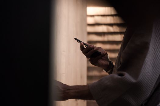 A person using a smartphone in a dimly lit indoor setting with moody lighting.