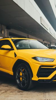 Vibrant yellow luxury SUV parked under an urban overpass. Sleek, contemporary design radiates extravagance.