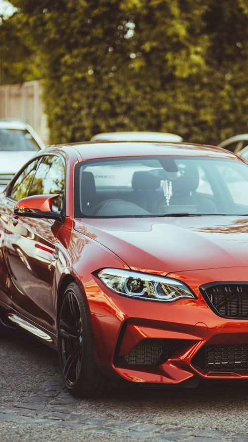 Free A shiny red luxury sports car parked outside on a sunny day, showcasing its sleek design. Stock Photo