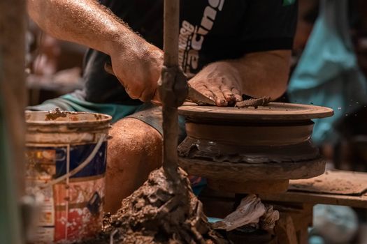 A potter shaping clay on a wheel, showcasing skill and craftsmanship. Hands covered in clay.